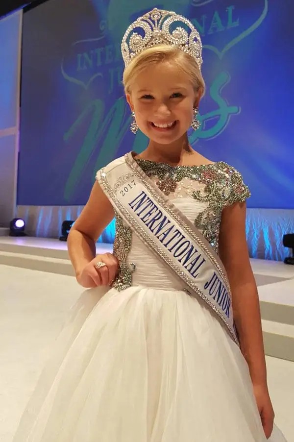 young model wearing a white pageant gown