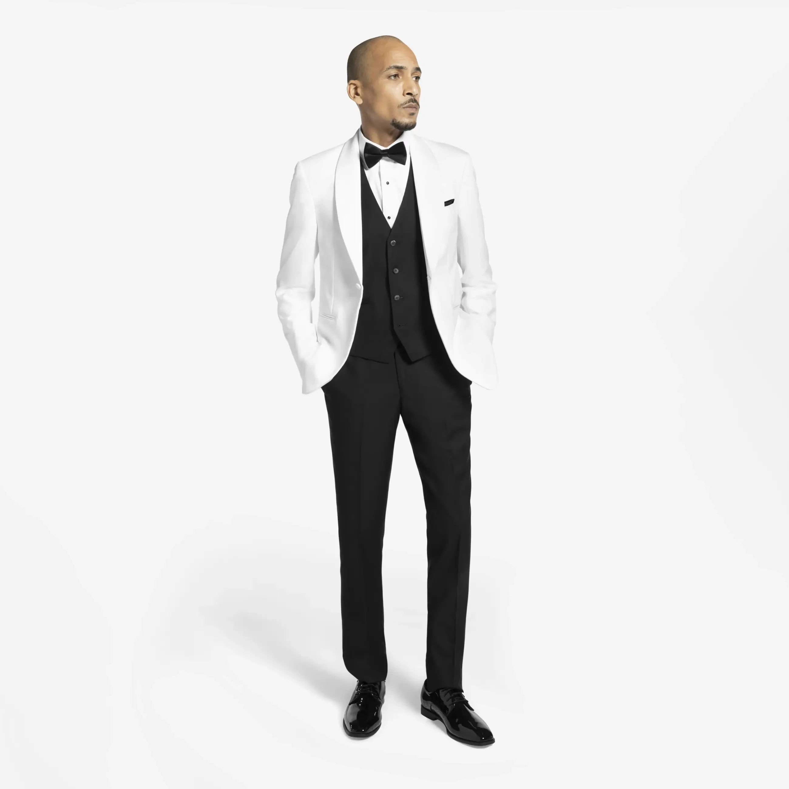 Man in formal attire, wearing a white tuxedo jacket, black waistcoat, and bow tie, stands confidently. Black dress pants and shiny shoes complete the look.