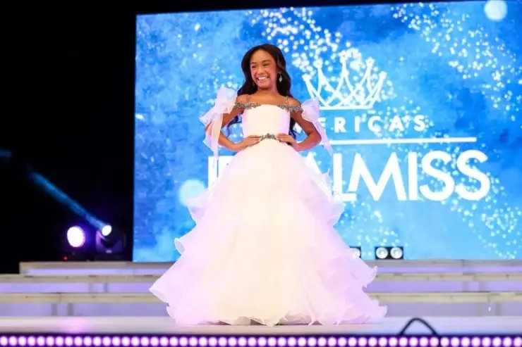 young model wearing a white pageant dress