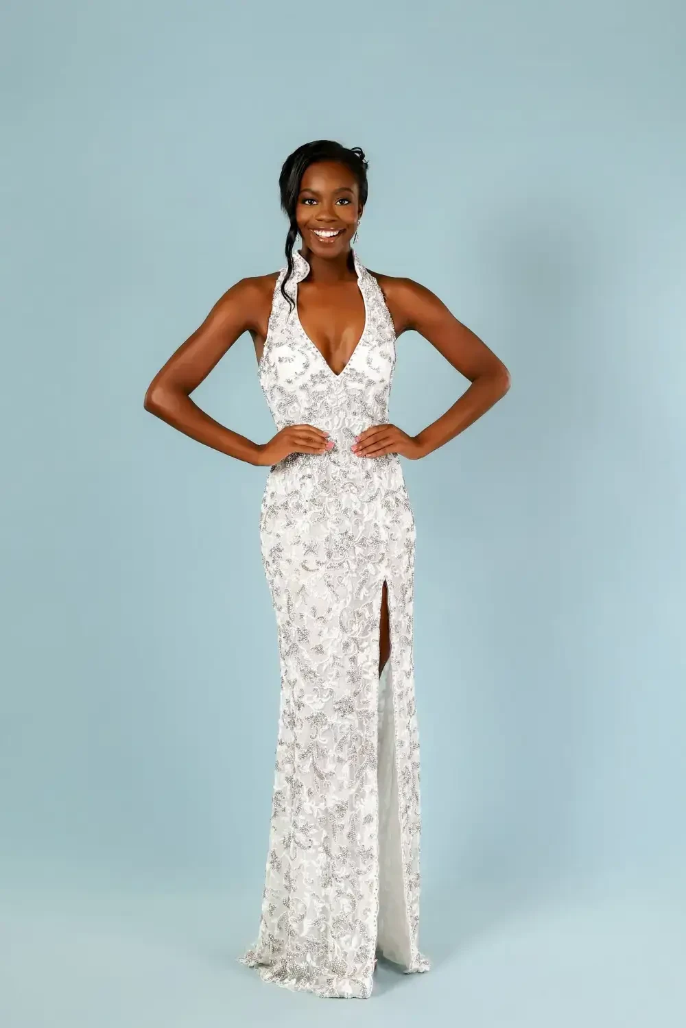 model is wearing a halter sparkly silver pageant gown