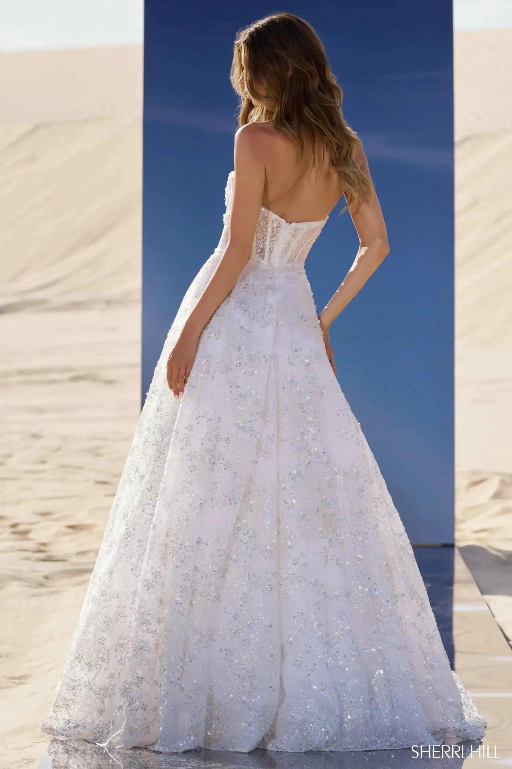 Model is wearing a white strapless sequin ball gown evening dress