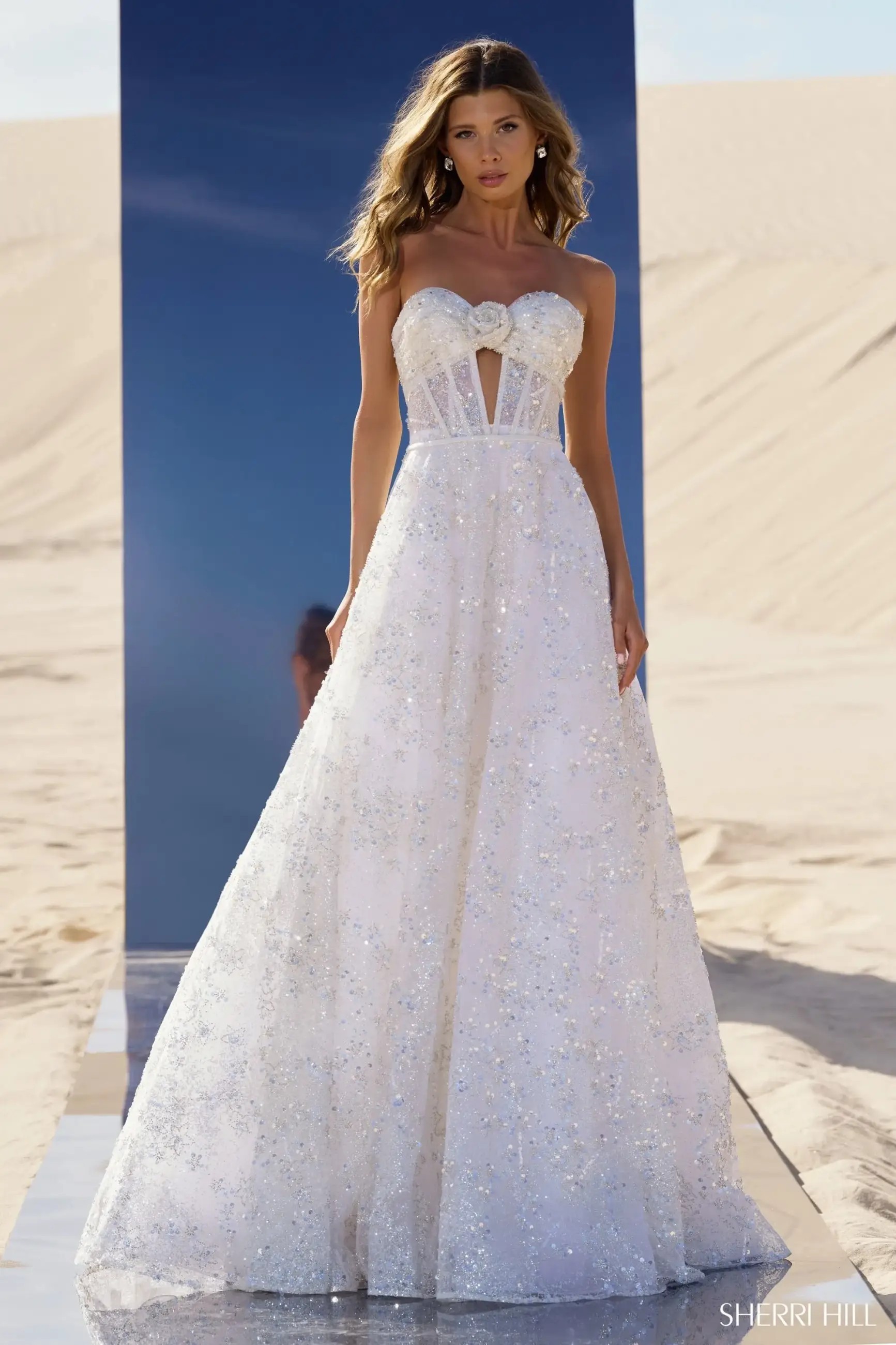 Model is wearing a white strapless sequin ball gown evening dress