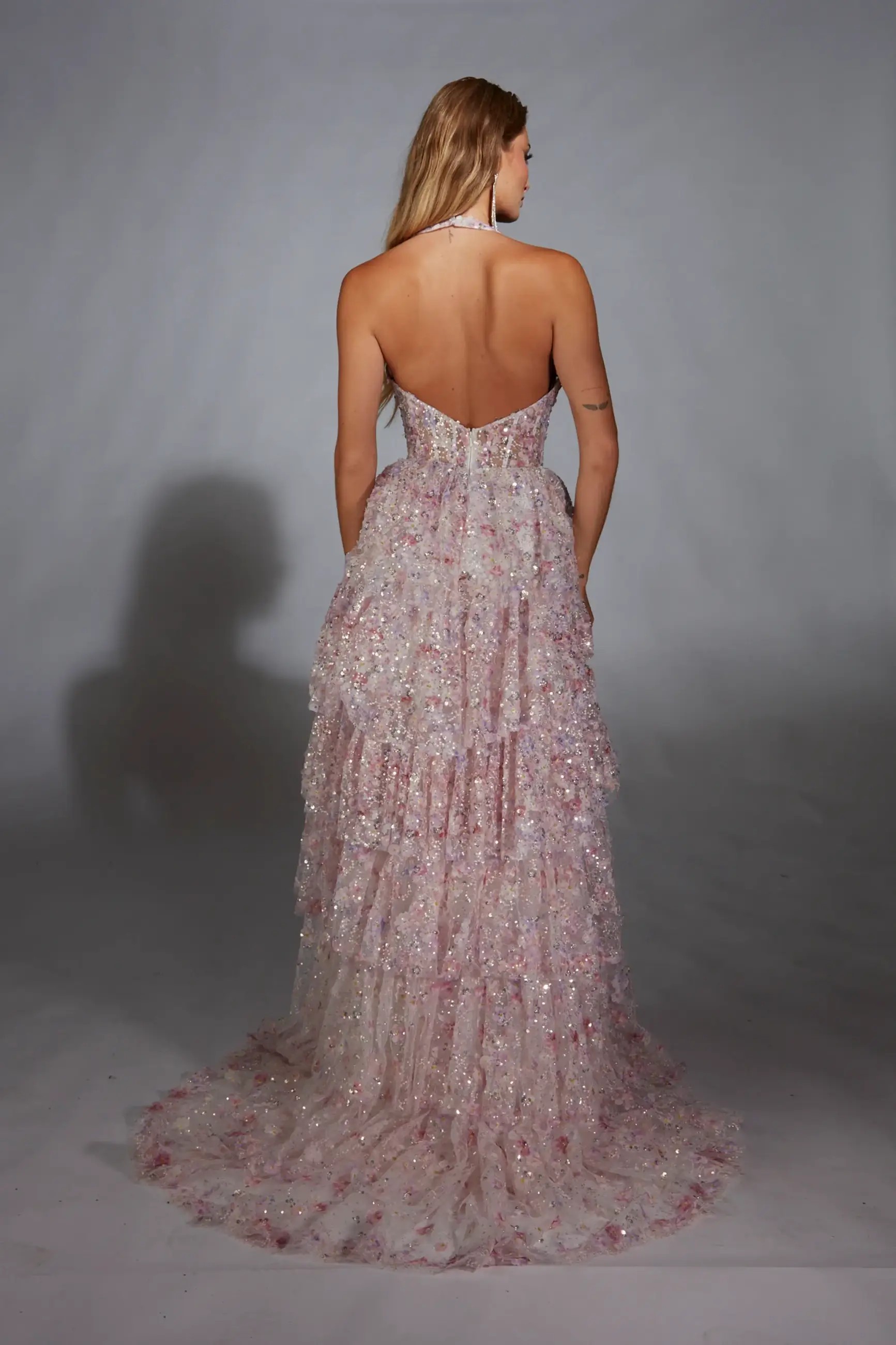Model is wearing a pink a-line dress with a halter neckline and thigh high slit