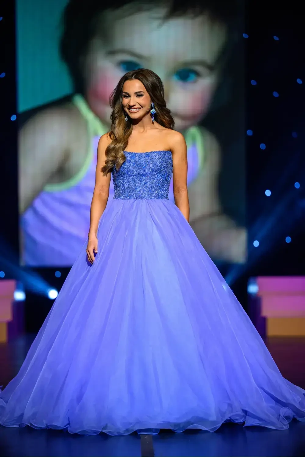 image shows a young girl wearing a pageant dress