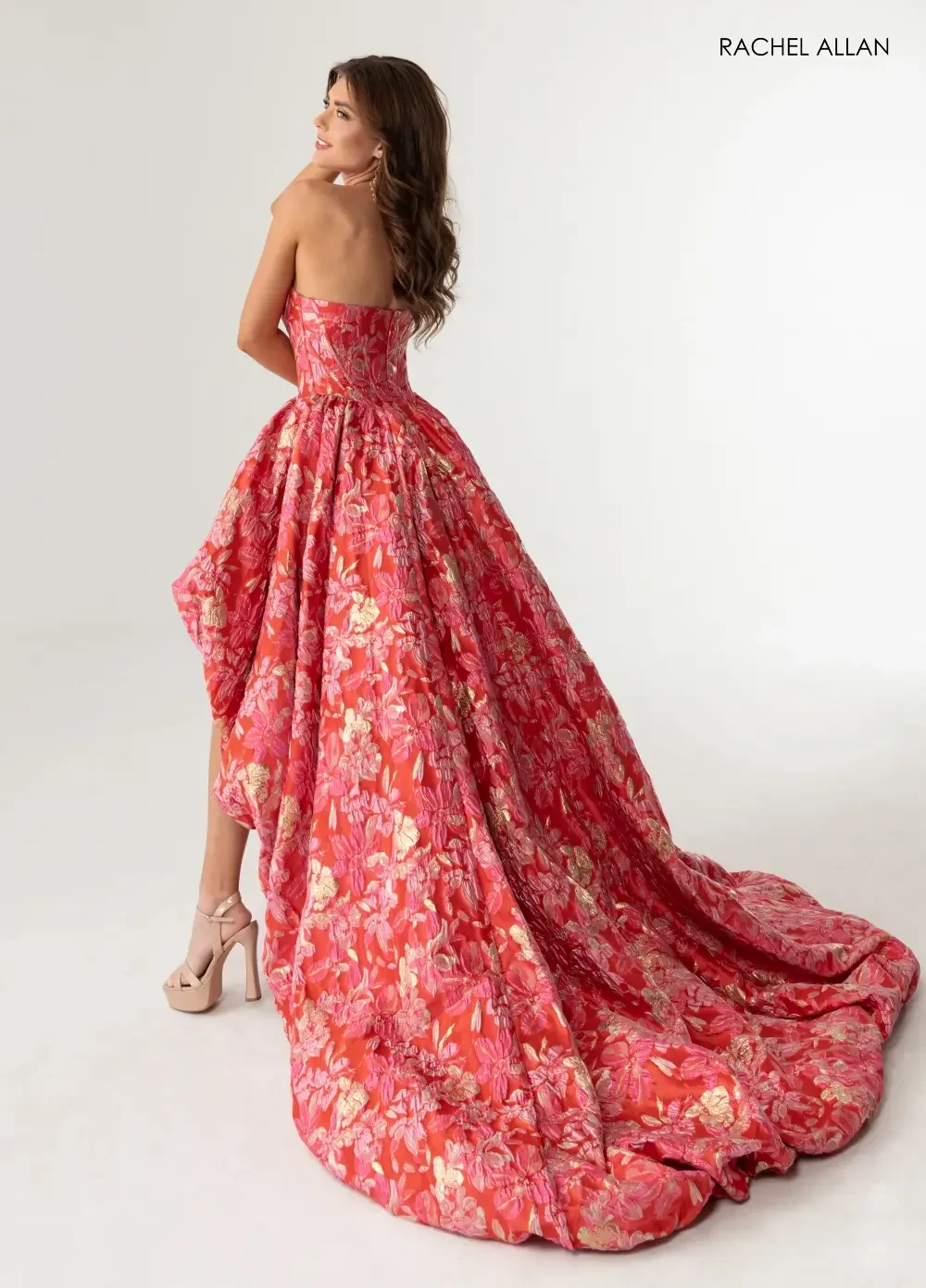 model is wearing a floral strapless high low prom dress